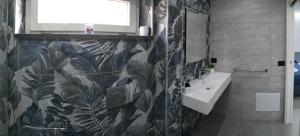 a bathroom with a sink and a leaf patterned wall at Affittacamere ONE in Frascineto