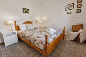 ein Schlafzimmer mit einem Holzbett und einem Stuhl in der Unterkunft Armstrong Cottage in Paynesville