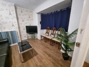 a living room with a couch and a tv at Cheerful 4/5 bed house - Heathrow in West Drayton