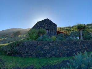 a stone house on a hill with a stone wall at Casa Las Sabinas in Guarazoca