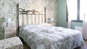 sypialnia z dużym łóżkiem z białą pościelą i tapetą w kwiaty w obiekcie Apartamentos La Chaparrina del Jerte w mieście El Torno