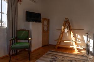 ein Wohnzimmer mit einem grünen Stuhl und einem Fernseher in der Unterkunft Casa Campo 1931 in Colonia del Sacramento