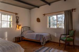 ein Schlafzimmer mit einem Bett, einem Stuhl und zwei Fenstern in der Unterkunft Casa Campo 1931 in Colonia del Sacramento + 27 Fotos