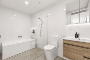 a bathroom with a toilet and a sink and a shower at Oceanview Penthouse by Experience Jervis Bay in Huskisson +18 photos