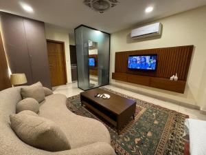 a living room with a couch and a tv at SkyLuxe Studio 2 with rooftop Pool & Self Check In in Islamabad