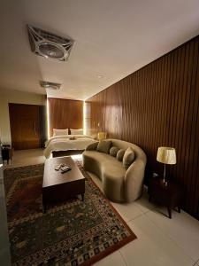 a bedroom with a bed and a couch and a table at SkyLuxe Studio 2 with rooftop Pool & Self Check In in Islamabad