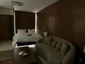 a hotel room with a bed and a couch and a table at SkyLuxe Studio 2 with rooftop Pool & Self Check In in Islamabad