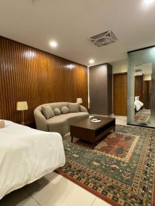 a hotel room with a bed and a couch at SkyLuxe Studio 2 with rooftop Pool & Self Check In in Islamabad