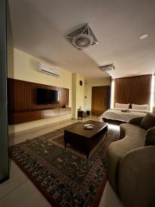a bedroom with a bed and a couch and a tv at SkyLuxe Studio 2 with rooftop Pool & Self Check In in Islamabad