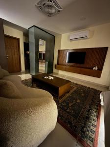 a living room with a couch and a flat screen tv at SkyLuxe Studio 2 with rooftop Pool & Self Check In in Islamabad