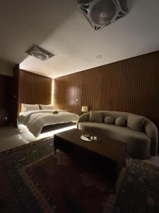 a bedroom with a bed and a couch and a table at SkyLuxe Studio 2 with rooftop Pool & Self Check In in Islamabad