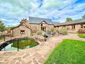 une grande maison en pierre avec un étang en face de celle-ci dans l'établissement Luxury 4 bed former hay loft SLEEPS 6, à Usk