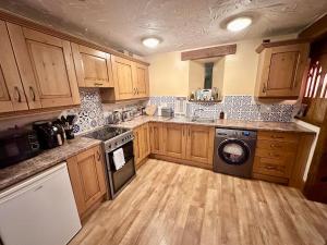 - une cuisine avec des placards en bois et un lave-linge dans l'établissement Luxury 4 bed former hay loft SLEEPS 6, à Usk