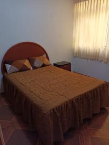une chambre avec un lit avec un couvre-lit marron et une fenêtre dans l'établissement Departamento con Estacionamiento en Tacna, à Tacna