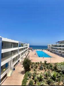 an apartment building with a swimming pool and the beach at Élégance et Sérénité Vue Mer Panoramique et Piscine Privée in Agadir +26 photos