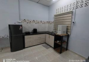 a kitchen with a black refrigerator in a room at Homestay Zainab Sg Dua Mslim With 100mbps Wifi in Kepala Batas