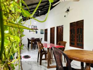a dining room with tables and chairs and plants at Pranu House in Nilaveli