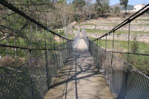 un pont suspendu sur une rivière sur un sentier dans l'établissement Hotel De Cerva, à Cerva