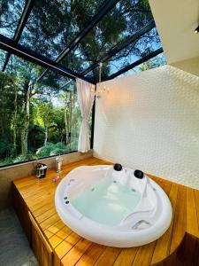 a large bath tub in a room with a large window at Loft com Piscina Privativa in Gramado