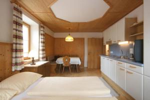 シュラートミンクにあるAppartements Schwaiger by Schladming-Appartementsのベッド1台付きの部屋、テーブル付きのキッチンが備わる客室です。