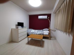 a bedroom with a bed and a dresser and a table at 下町の穴場 キッチン完備 長期滞在に最適なお部屋 Rapyuta monthly apartment in Kyoto