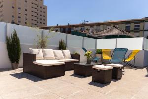 a patio with wicker furniture and chairs on a rooftop at Douro Garden and Rooftop Home 1 in Vila Nova de Gaia