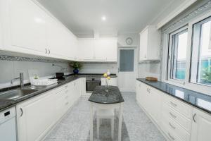 a kitchen with white cabinets and a table in it at Douro Garden and Rooftop Home 1 in Vila Nova de Gaia