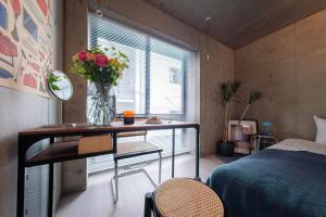 a bedroom with a table with a vase of flowers on it at Ueno Grand Maison Hotel in Tokyo