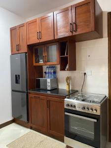 a kitchen with wooden cabinets and a stainless steel refrigerator at makazi yetu - Makongo Area 4 in Dar es Salaam