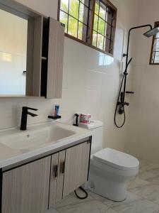 a white bathroom with a sink and a toilet at makazi yetu - Makongo Area 4 in Dar es Salaam