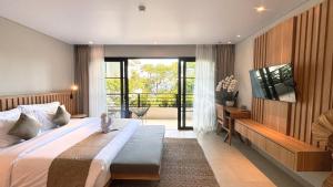 a bedroom with a bed and a television and a balcony at ZIN Canggu Resort & Villas in Canggu