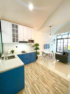 a kitchen with blue cabinets and a living room at Dirumahjogja - Villa 2 in Jarakan
