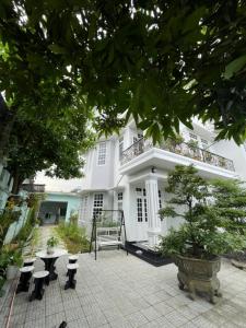 フエにあるNhat Long Homestayの白い建物で、パティオ(テーブル、ベンチ付)が備わります。