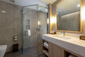 ein Badezimmer mit Glasdusche und Waschbecken in der Unterkunft Khaolak Merlin Resort in Khao Lak