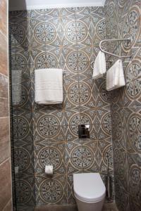 a bathroom with a toilet and a tiled wall at Hotel Boutique Restaurant Gloria in Tirana