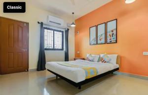 ein Schlafzimmer mit einem Bett mit einer orangefarbenen Wand in der Unterkunft Exotic stay in Nerul