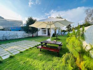 a picnic table with an umbrella in a yard at Nhà Vườn 994 Trần Phú , Lộc Châu thành phố bảo lộc in Ấp Tân Hà