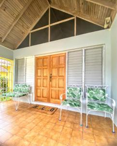 a porch with two chairs and a wooden door at Yancey Largo Villa with Private Pool in Montego Bay
