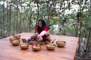 Eine Frau, die an einem Tisch sitzt und Schüsseln drauf hat. in der Unterkunft Na Tuệ An-Homestay 81 Võ Văn Kiệt in Tuyên Quang