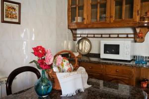 a kitchen with a table with a vase of flowers and a microwave at Casa de Campo Neves in Montalegre