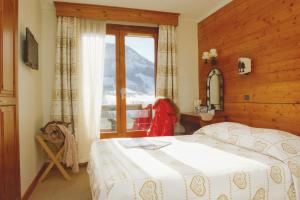 ein Schlafzimmer mit einem Bett und einem großen Fenster in der Unterkunft Hôtel Vacances Bleues Les Chalets du Prariand in Megève