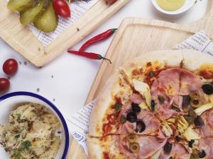 a pizza on a cutting board next to a bowl of food at Cachet Boutique Kunming Artime in Kunming