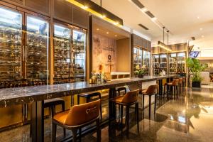 a bar in a restaurant with brown stools at Cachet Boutique Kunming Artime in Kunming