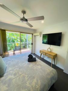 a bedroom with a bed and a flat screen tv at Ocean Tropics Lush Villa at Aanuka Resort in Coffs Harbour +15 photos