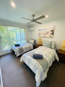 a bedroom with two beds and a ceiling fan at Ocean Tropics Lush Villa at Aanuka Resort in Coffs Harbour