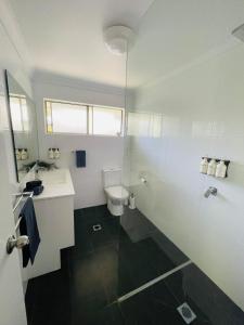 a white bathroom with a toilet and a sink at Ocean Tropics Lush Villa at Aanuka Resort in Coffs Harbour