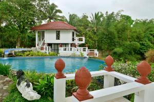 a house with a swimming pool and a white fence at Porta Verde Resort Cavinti Laguna with Lake View in Cavinti
