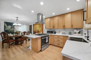 a kitchen with wooden cabinets and a dining table at Pirate Cove: Heated Pool, Arcade, Play, More! in Garden Grove