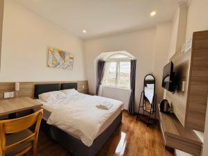 a bedroom with a bed and a desk and a television at Bee Luxury Dalat Hotel in Xuan An +31 photos