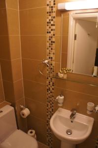 a bathroom with a sink and a toilet and a mirror at Sapphire Hotel London in London